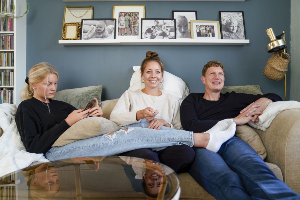 Familj som kollar på TV i soffan