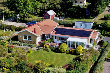 Flygbild över tegelvilla med installerade solceller på taket.