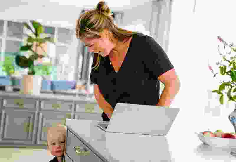 Mamma och ett barn vid en dator i ett kök