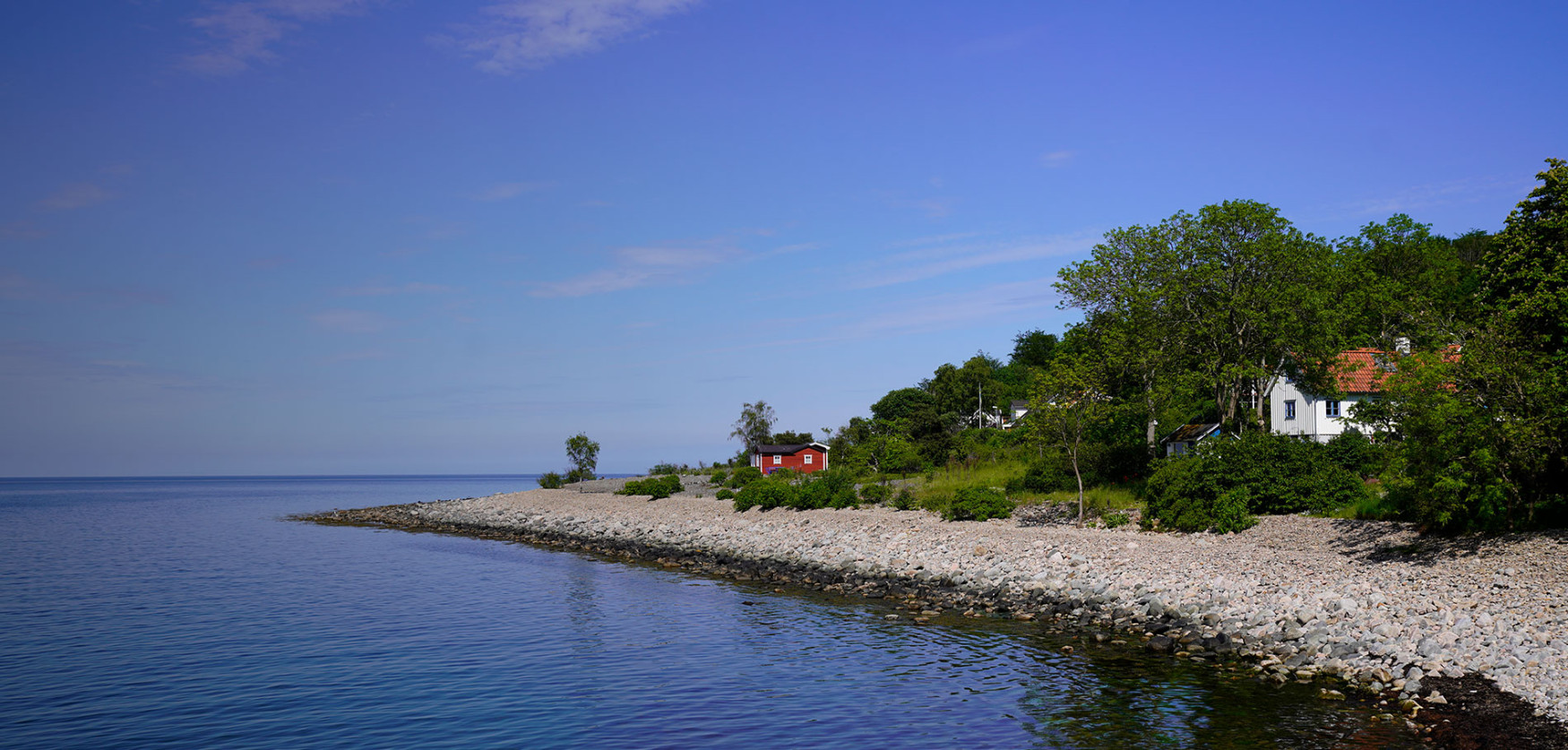 Hus vid havet och liten röd stuga