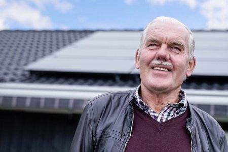 Glad man framför hus med solceller på taket