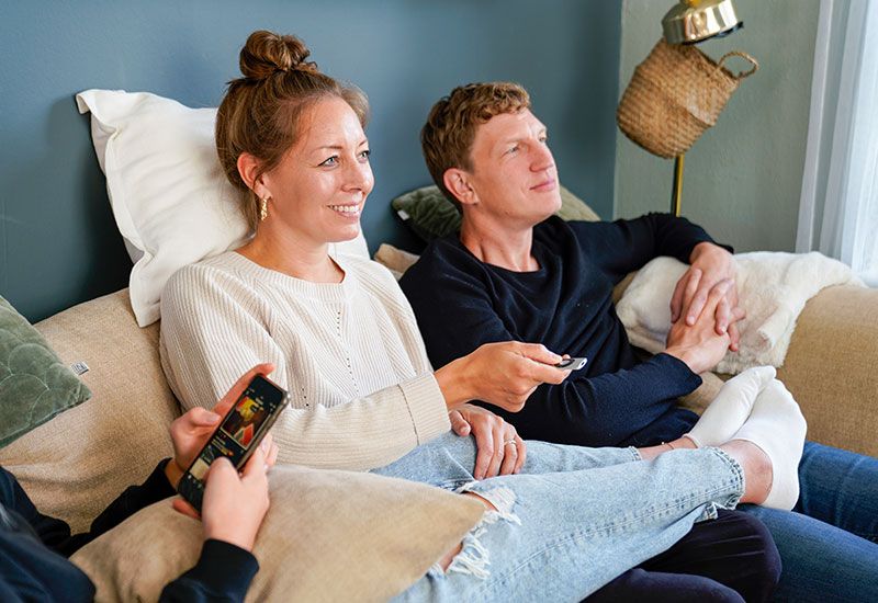 Man och kvinna i soffa som tittar på TV