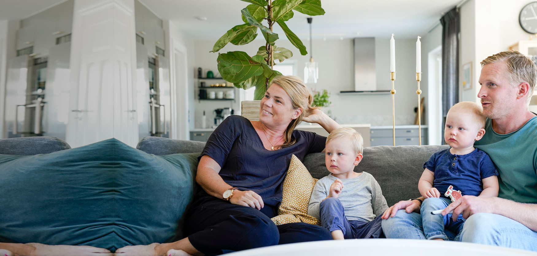 Familj med två små barn sitter i soffan och tittar på TV